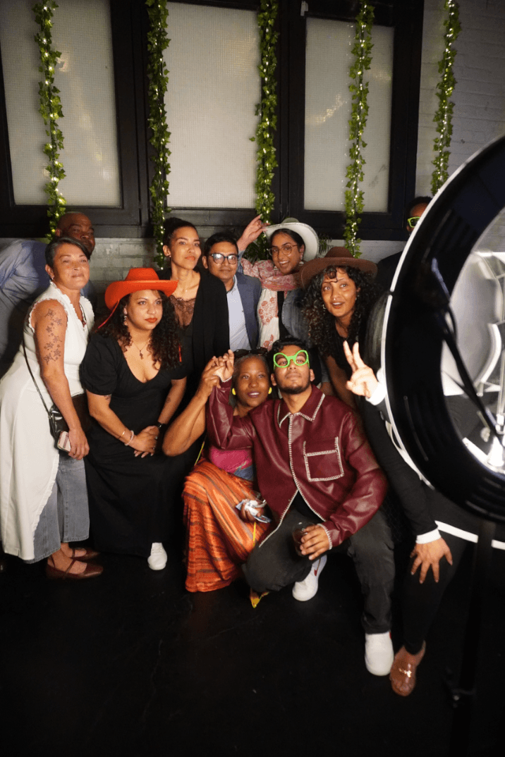 A large group celebrating together in front of a green garland backdrop